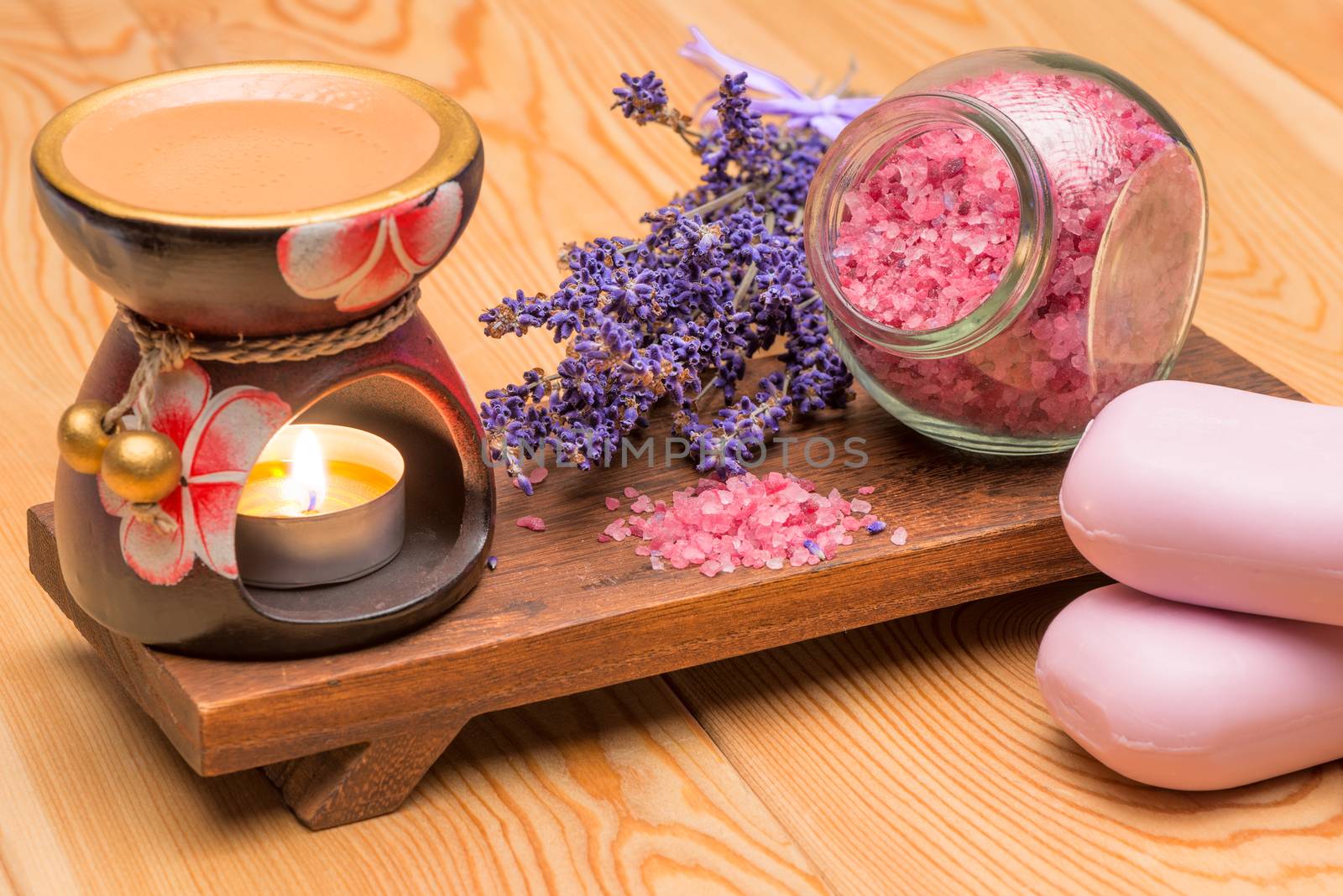 lavender soap and lavender sea salt on a wooden stand with a burning candle