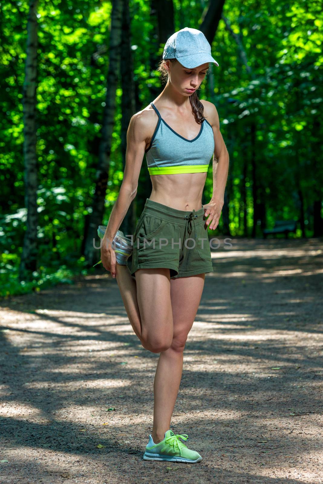 pretty athletic girl warms up her muscles before jogging in the park