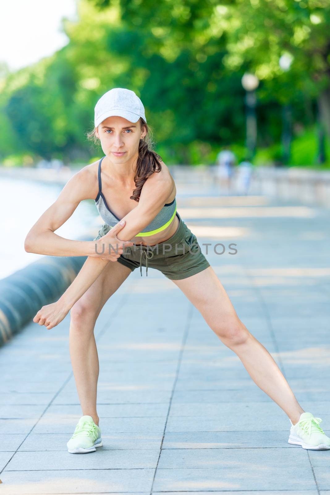 warm-up on the city's quay before jogging, portrait of a female athlete