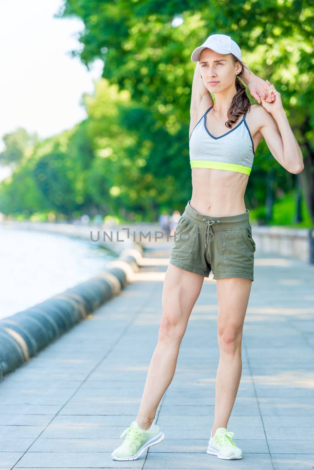 girl with a muscular figure is warming up on the city embankment by kosmsos111