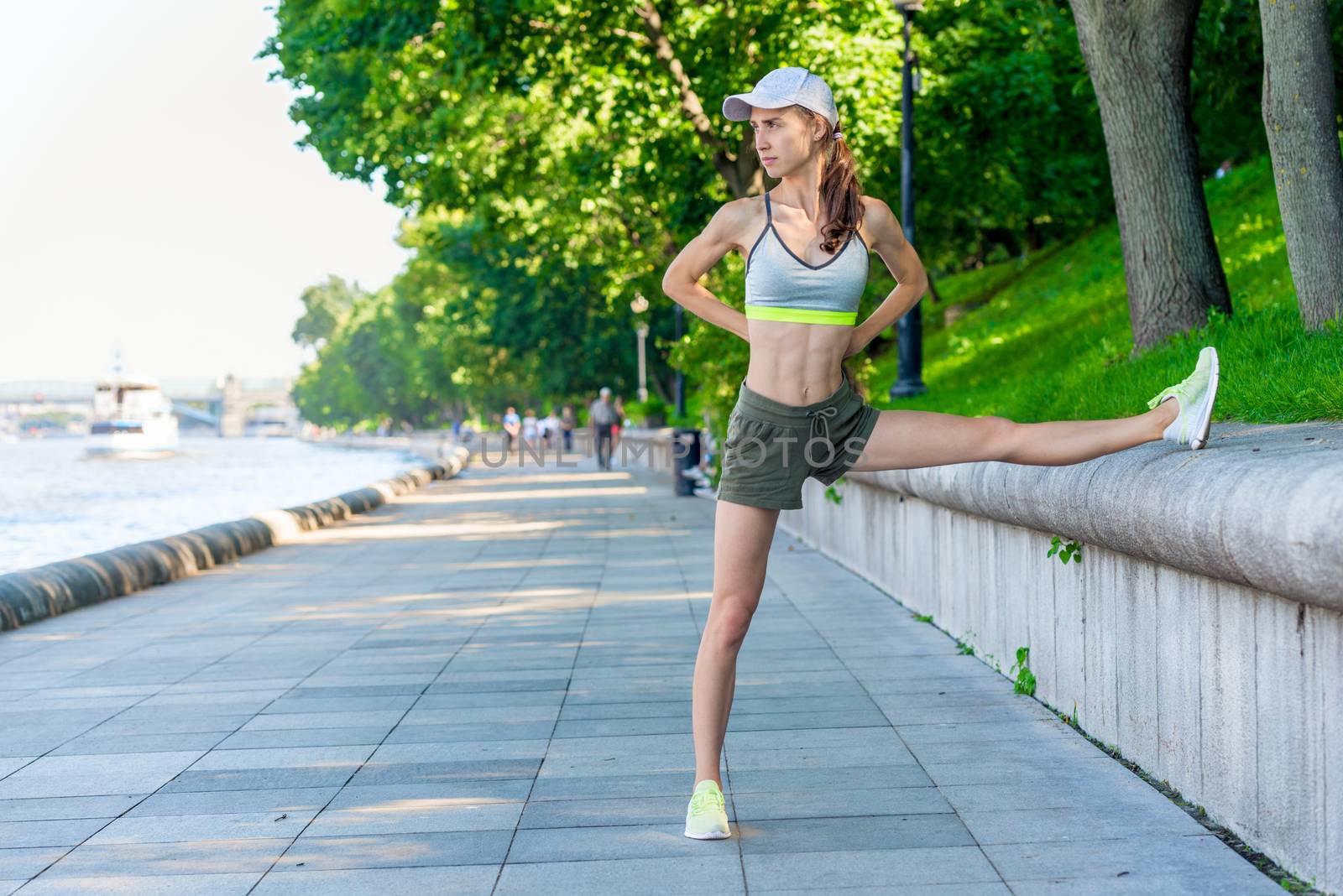 sporty woman warming up before jogging in a city park, portrait by kosmsos111