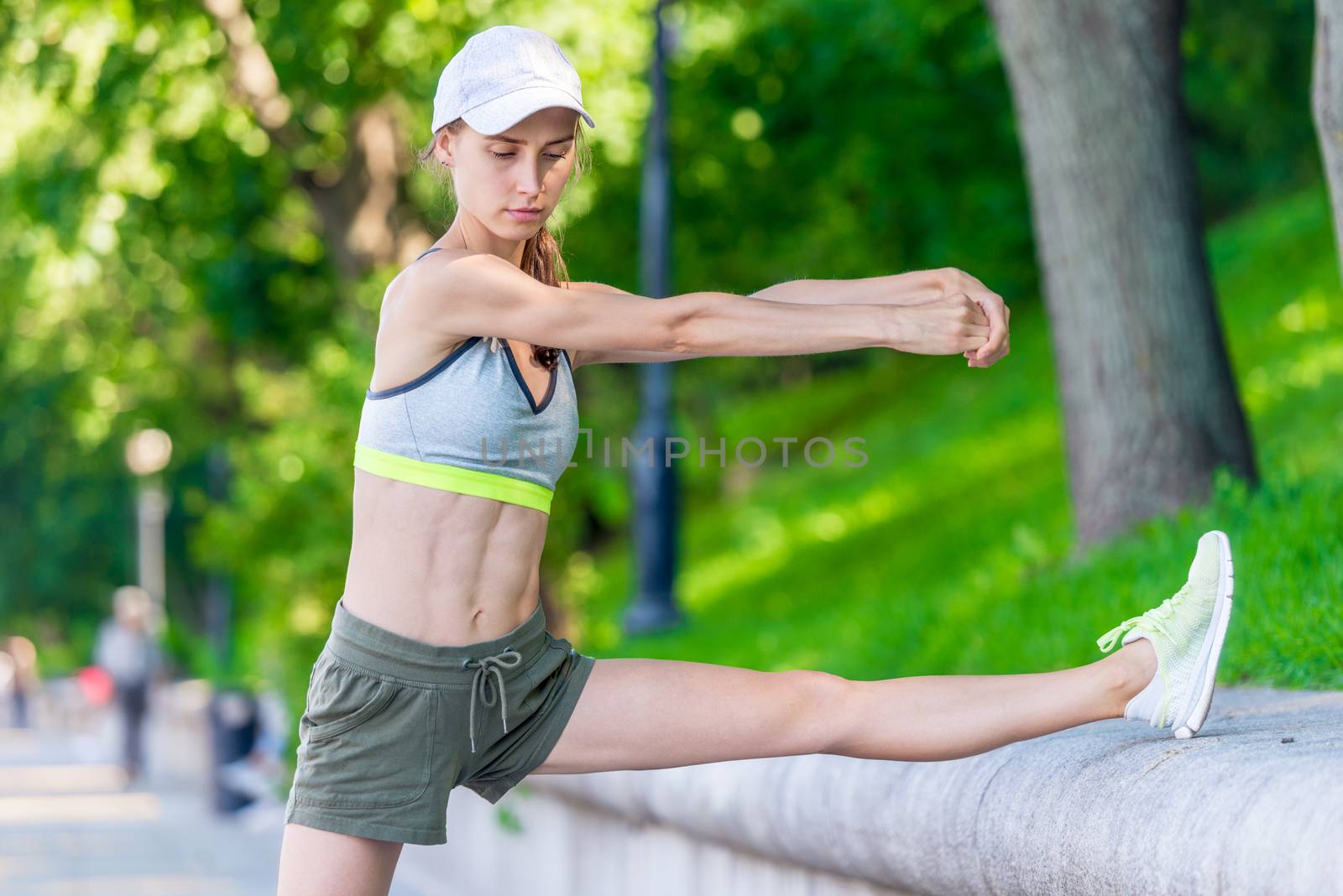 muscular woman warming up before jogging in a city park, portrait on the embankment