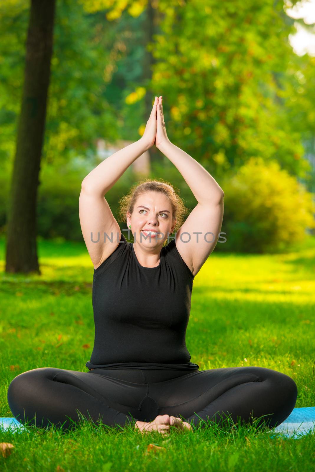 fat woman doing yoga in the park in the lotus position by kosmsos111