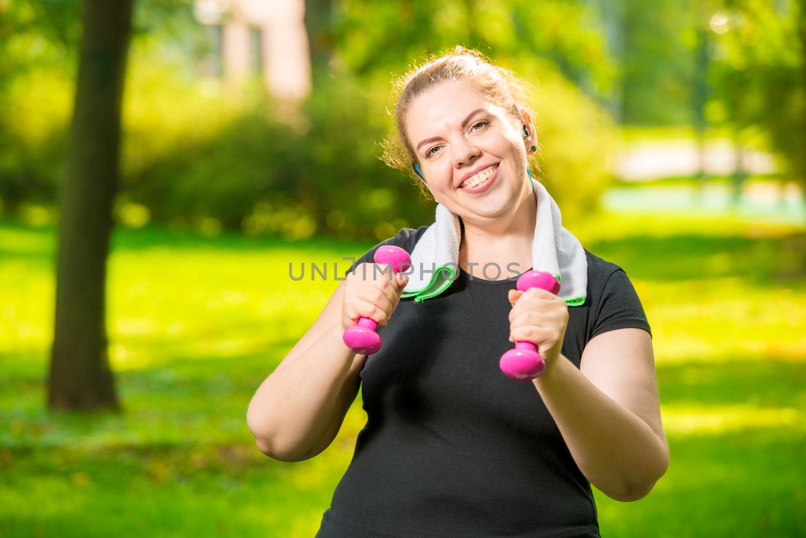 happy fat woman with dumbbells in the park during workout