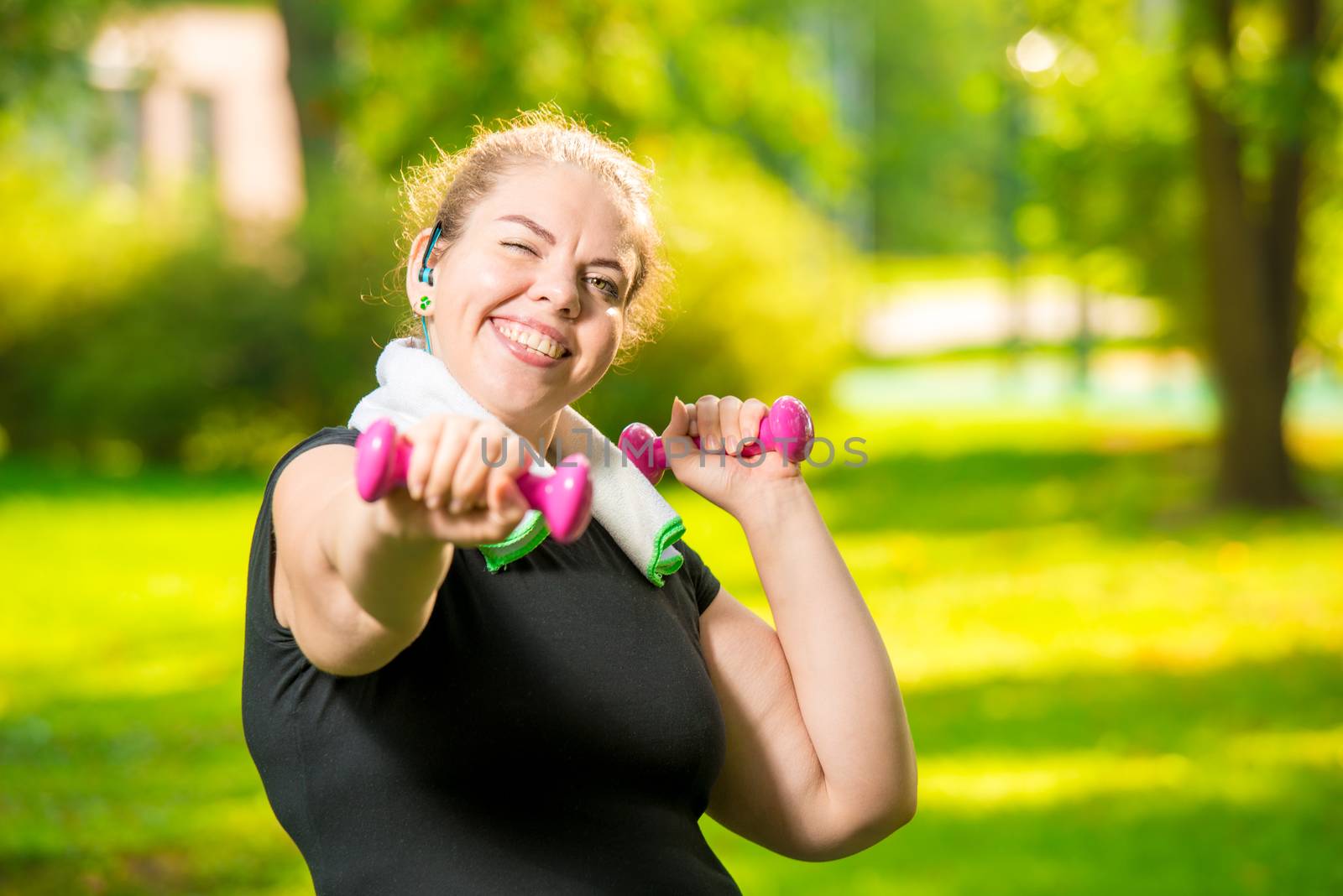 portrait of a happy fat woman with dumbbells in the park during workout