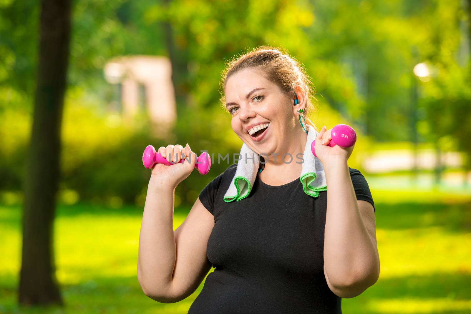 horizontal portrait of a happy plump woman with dumbbells in the by kosmsos111