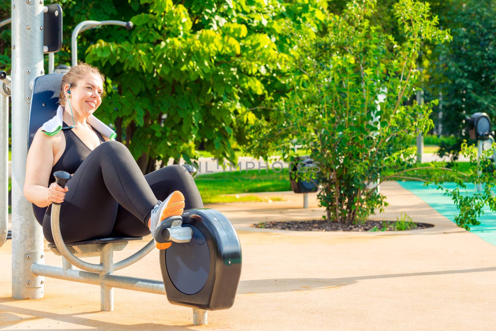 active oversized woman doing exercise on a stationary bike in a city park