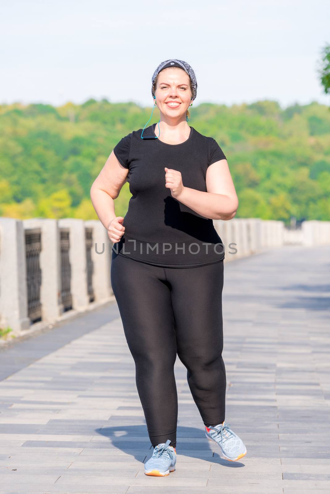 portrait of a fat active woman working on her figure - morning run in a city park