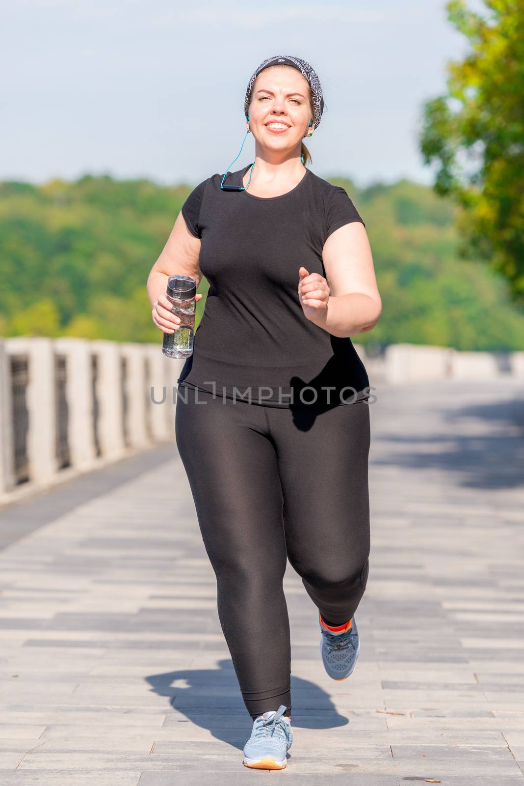 plus size woman with a bottle of water during her morning jog in a city park