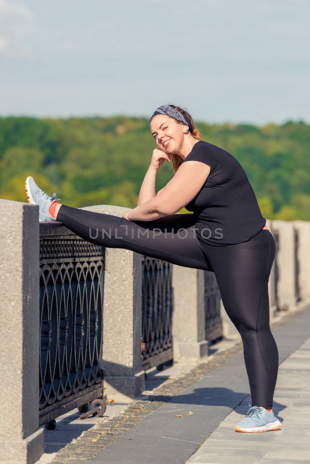 young woman oversized doing stretching exercises on the embankme by kosmsos111