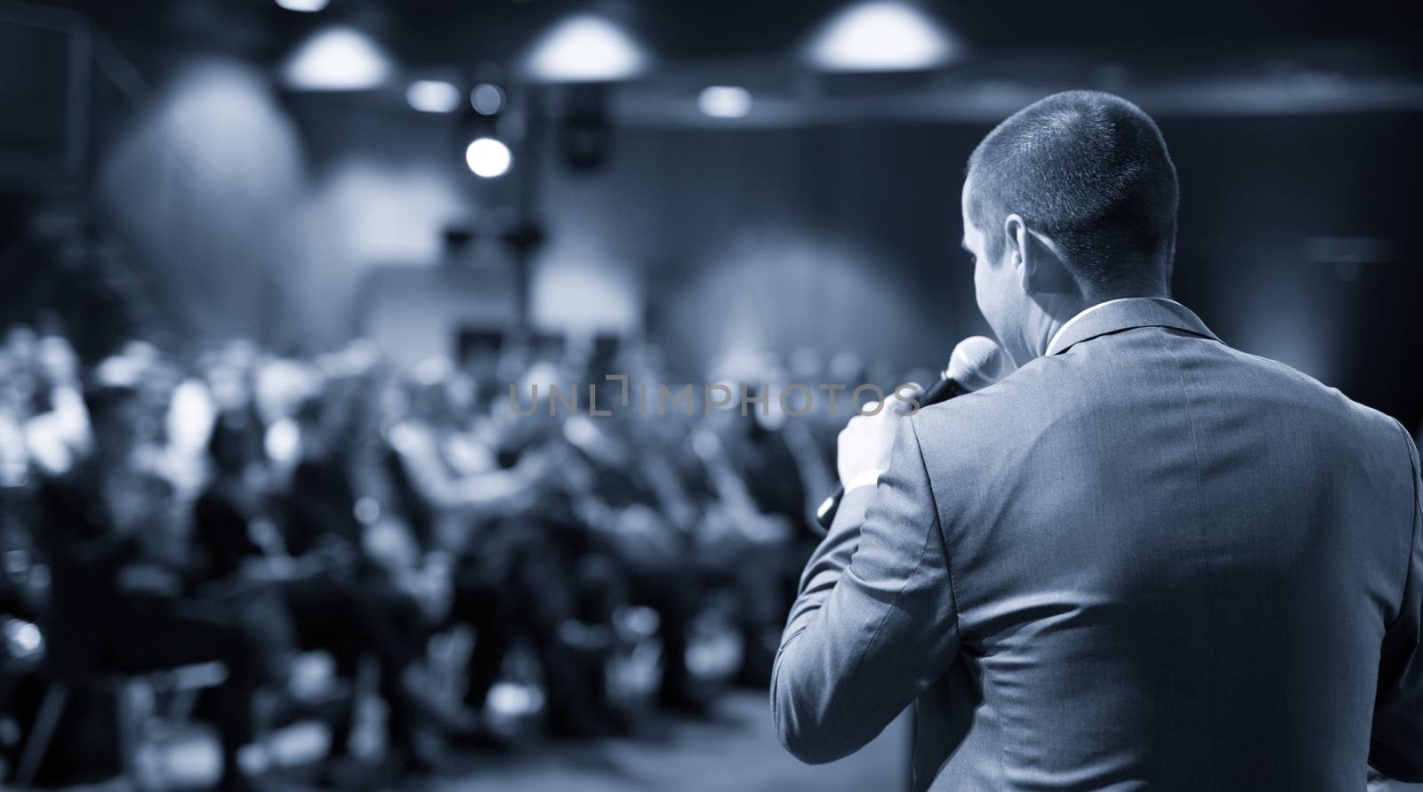 Speaker giving a talk on corporate business conference. Unrecognizable people in audience at conference hall. Business and Entrepreneurship event.