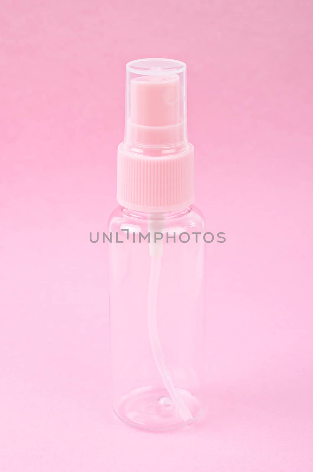 Clear pink plastic bottle spray on pink background.