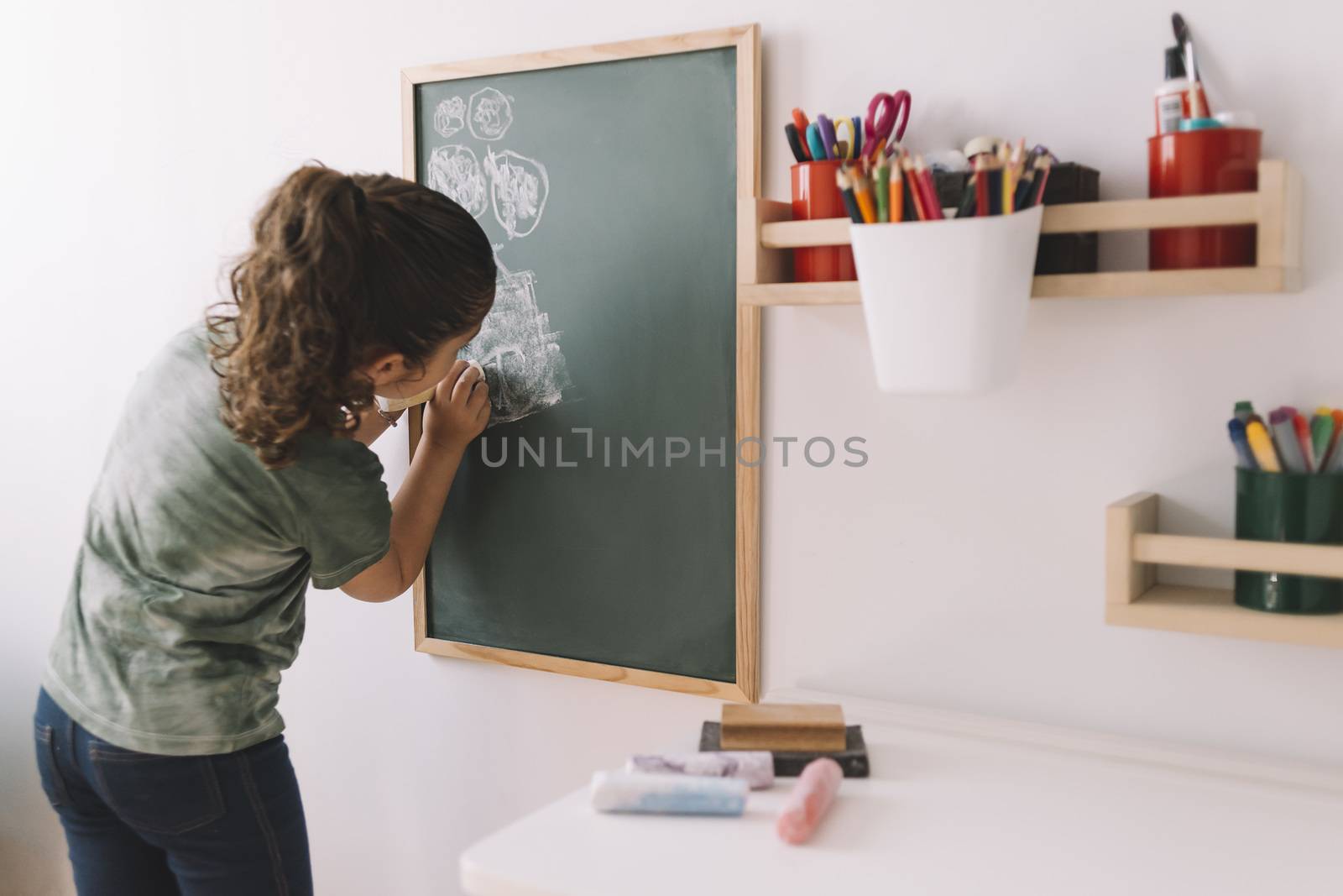 little girl drawing with a chalk on a blackboard at her room at home, copy space for text