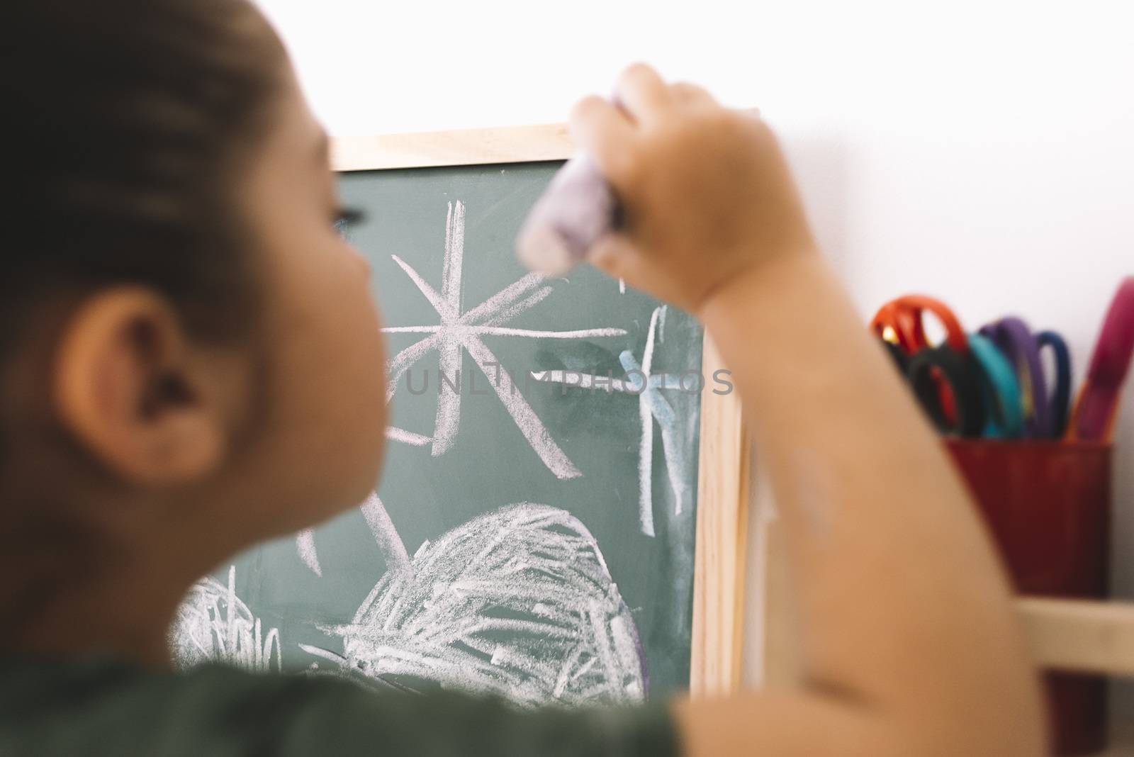 little girl drawing with a chalk on a blackboard at her room at home, copy space for text