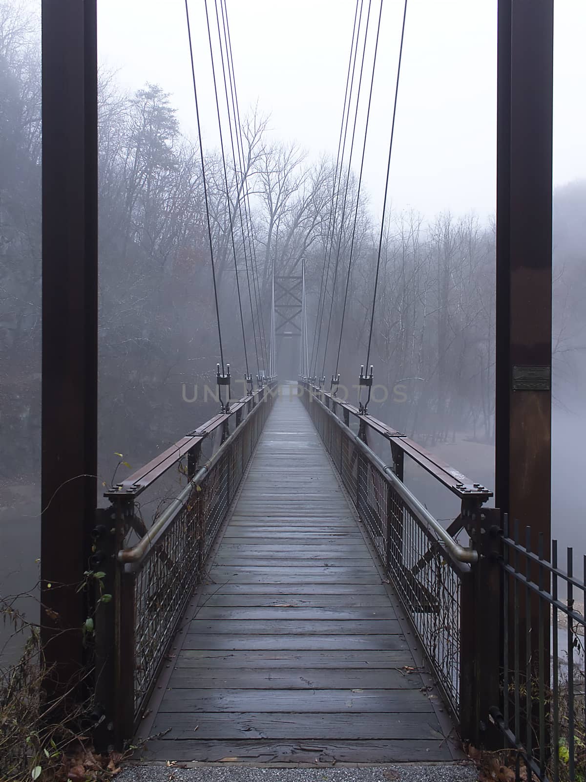Pedestrian suspension bridge over river with fog