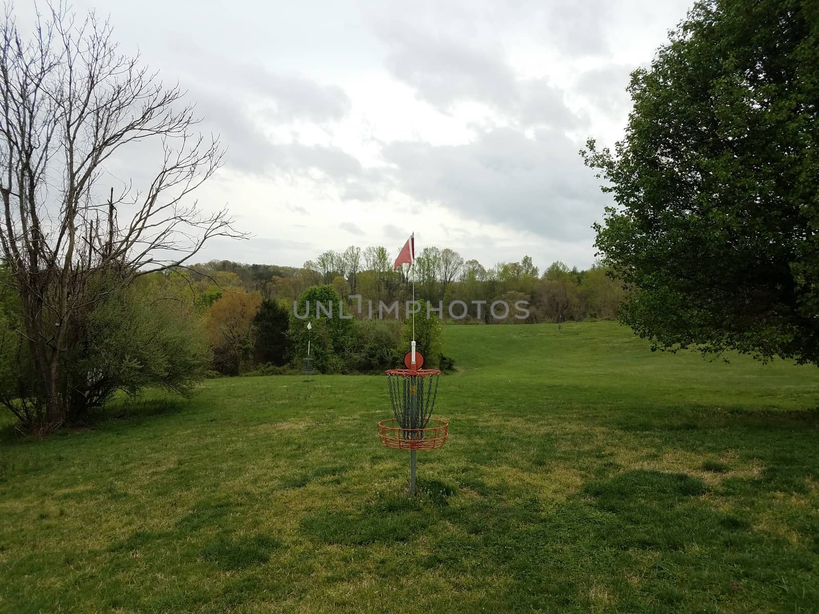 red disc golf chain basket or hole with green grass by stockphotofan1