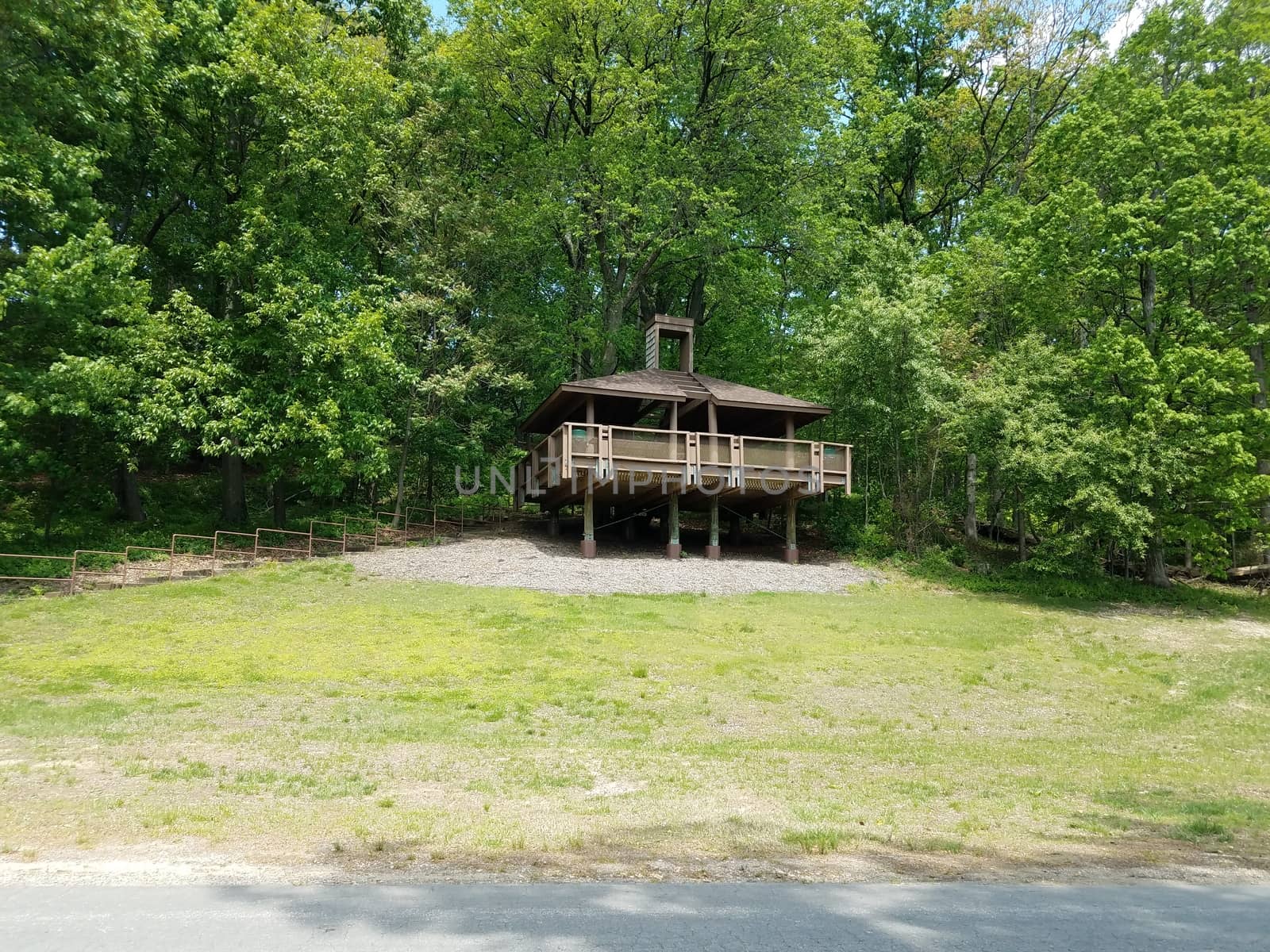 brown wooden picnic pavilion on hill with green grass and trees by stockphotofan1