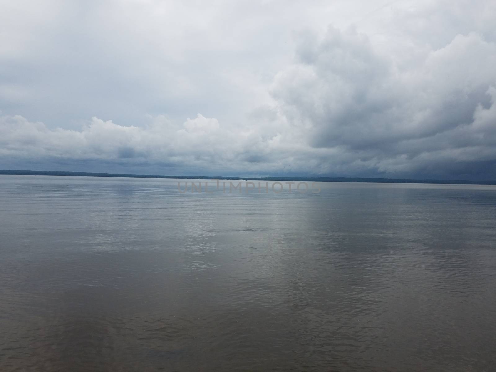 calm water in river or lake and white clouds and hills