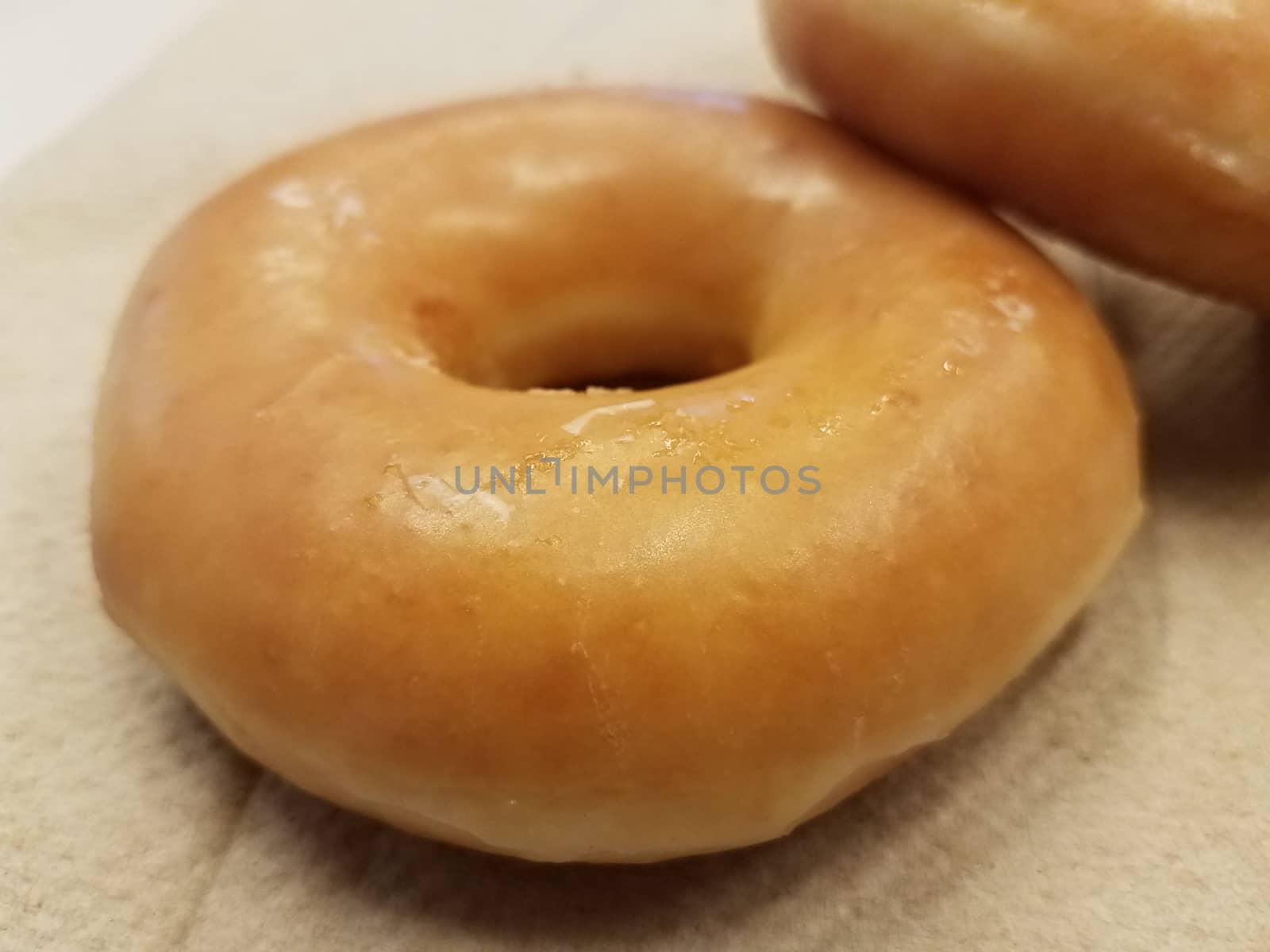 sweet glazed sugar donut on brown paper towel by stockphotofan1