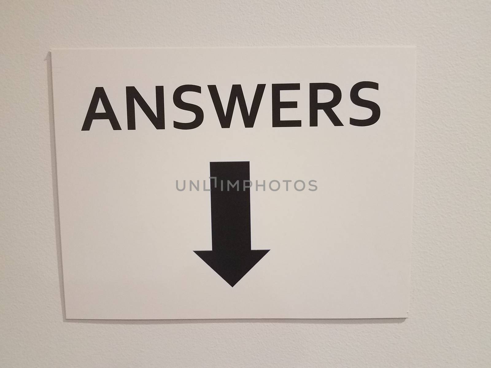 white paper answers sign with black down arrow on wall by stockphotofan1