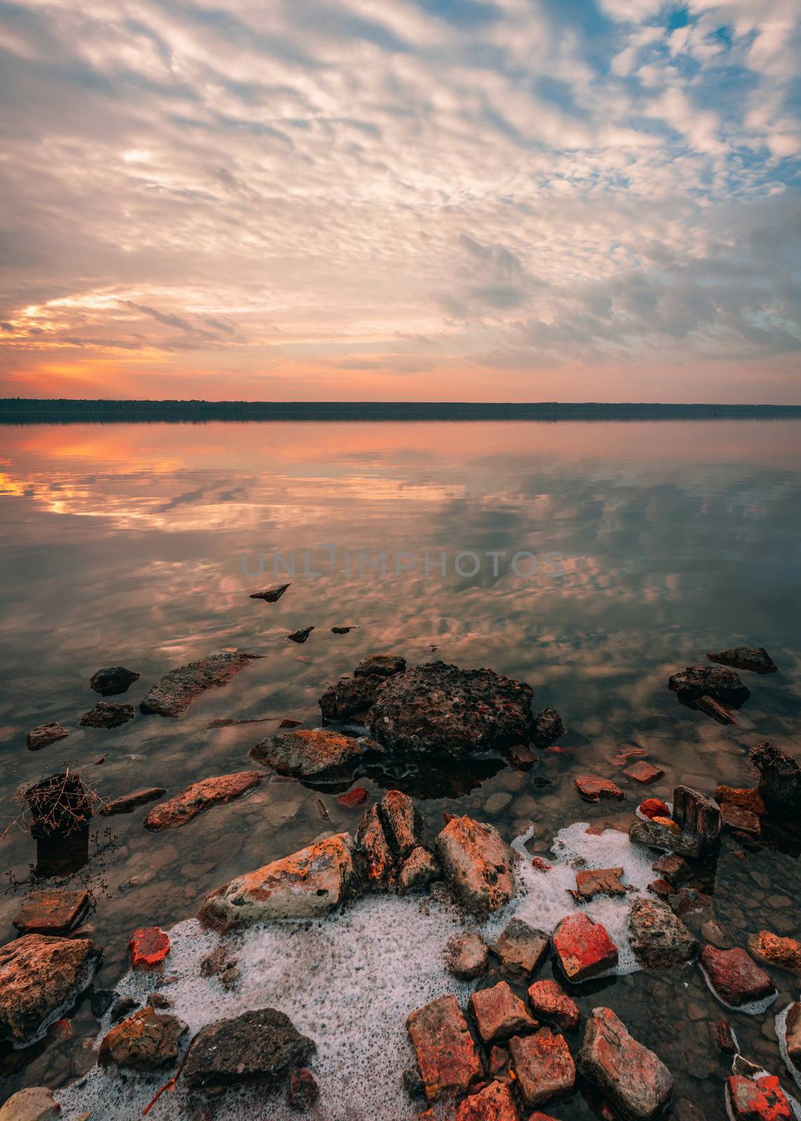 Stones on the lake in the red light of summer sunset