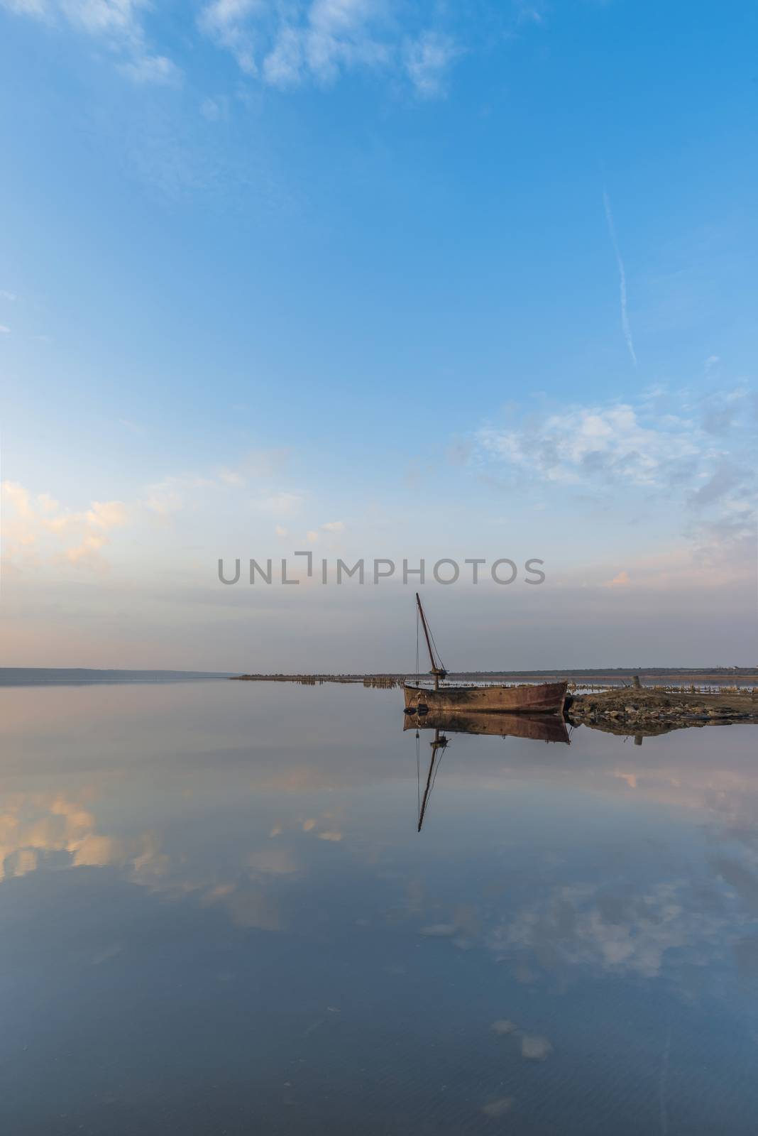 Panoramic view of the lake and the old boat at sunset of a summer day