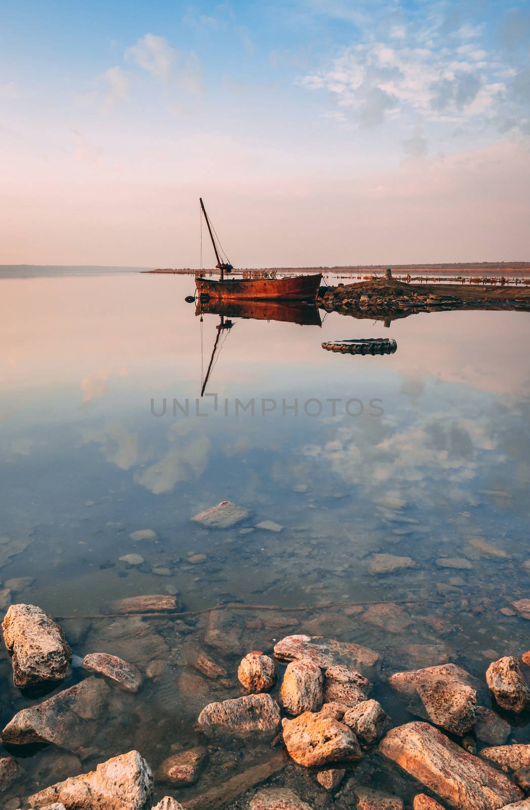 Panoramic view of the lake and the old boat at sunset of a summer day