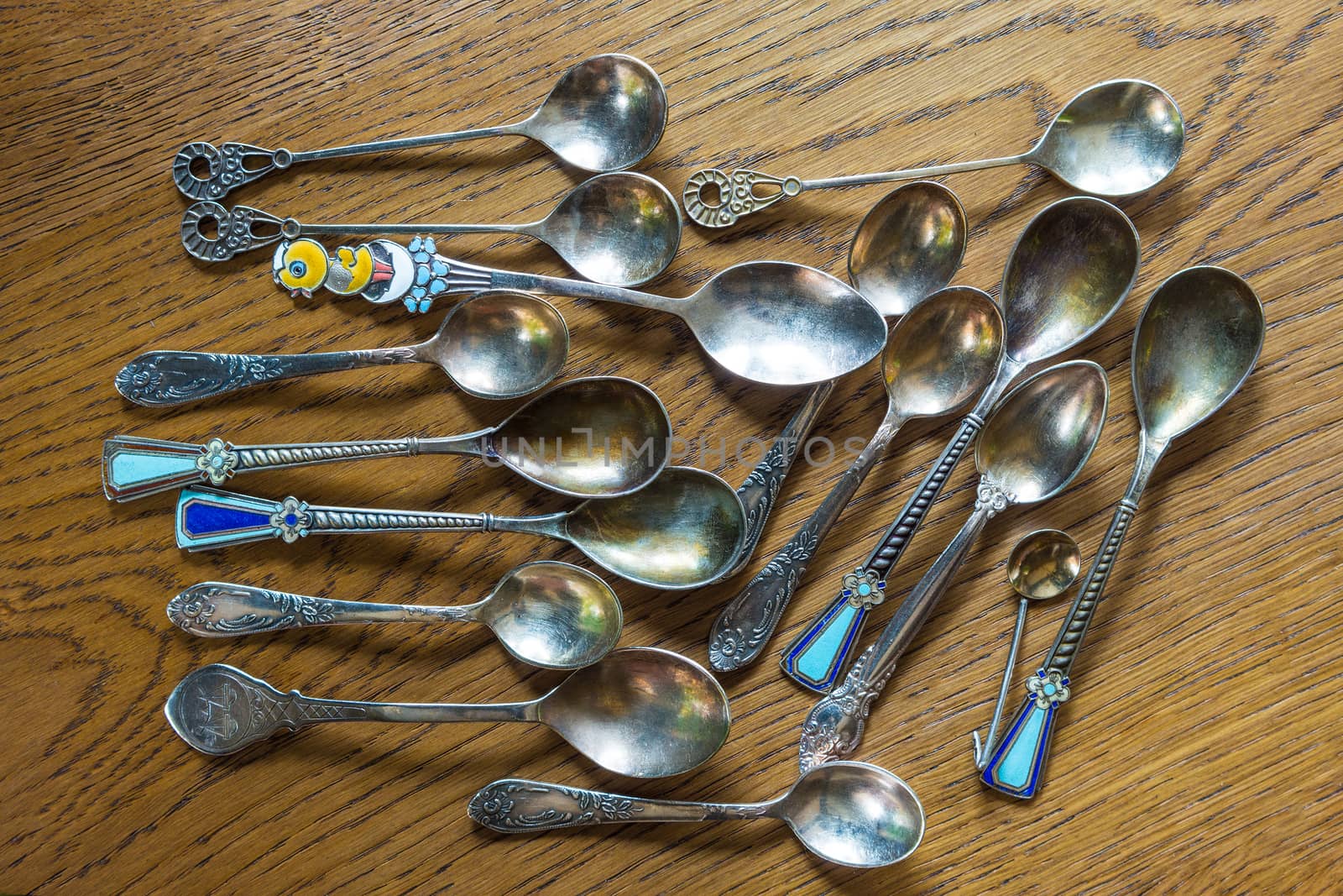 A pile of vintage, decorative spoons on an oak table by ben44