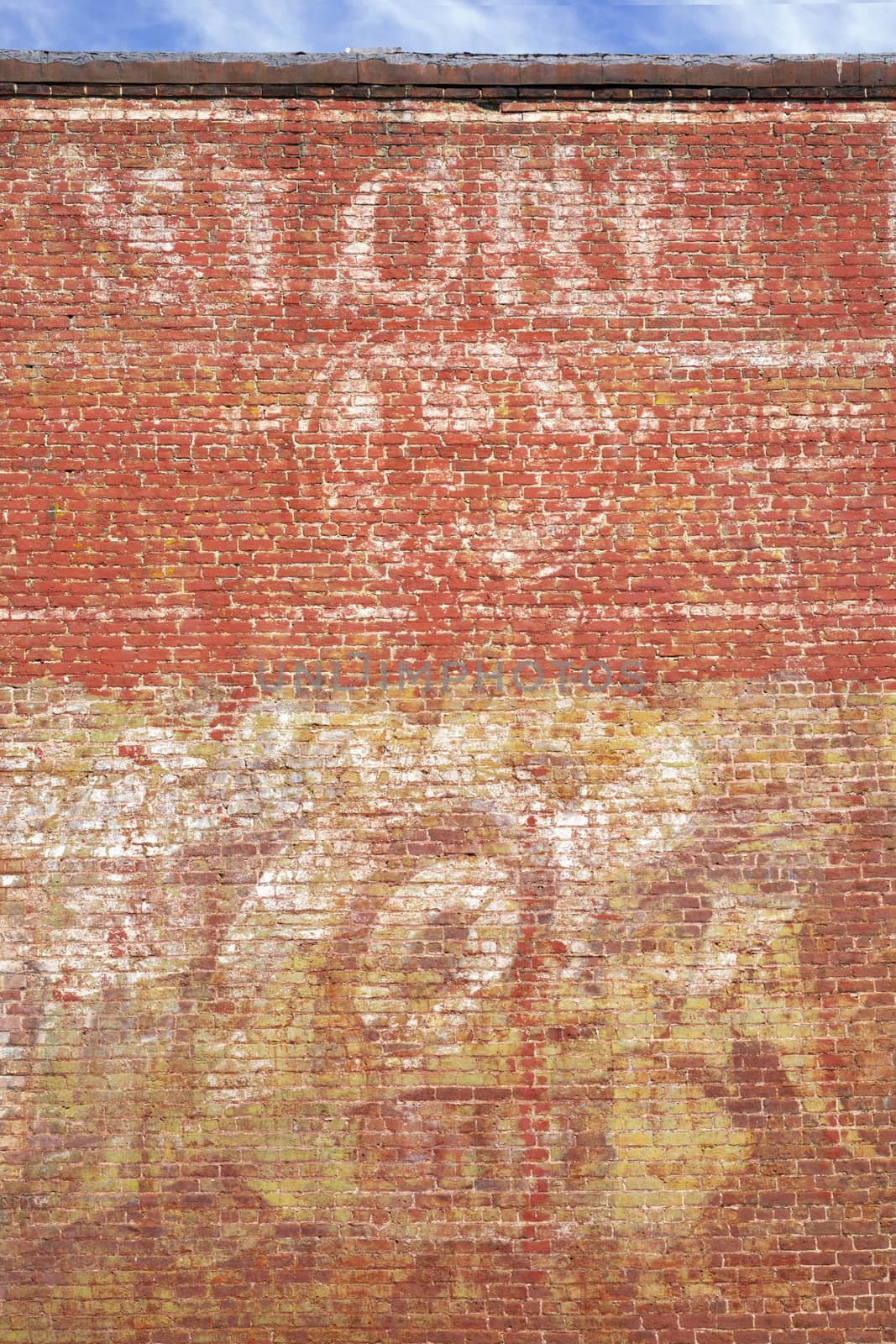 The faded paint of old advertising seen on the side of a brick building in a small town.