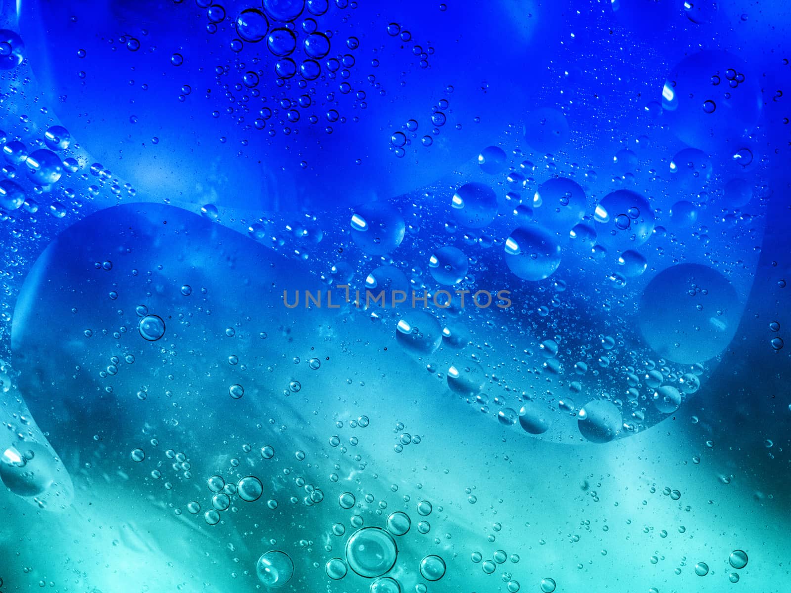 Bubbles in oil and water mixture with blue and green coloring.