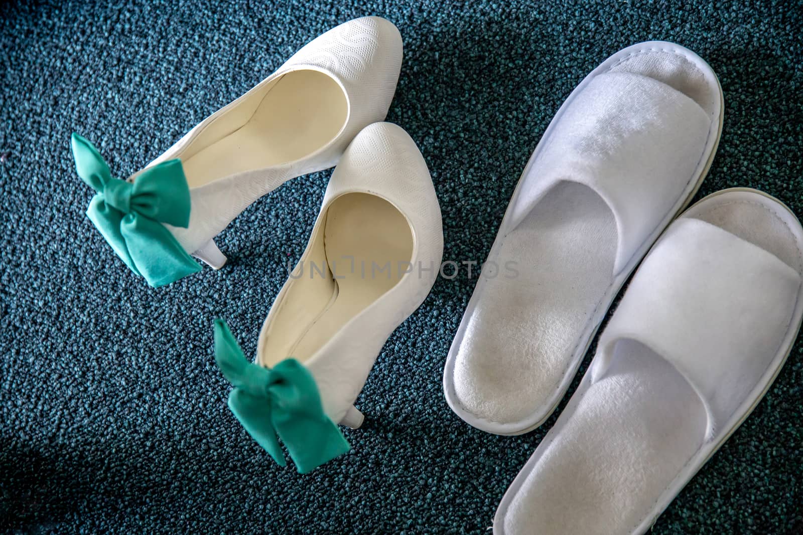 White bridal shoes and wedding slippers on carpet. Wedding shoes with ribbons and white slippers.