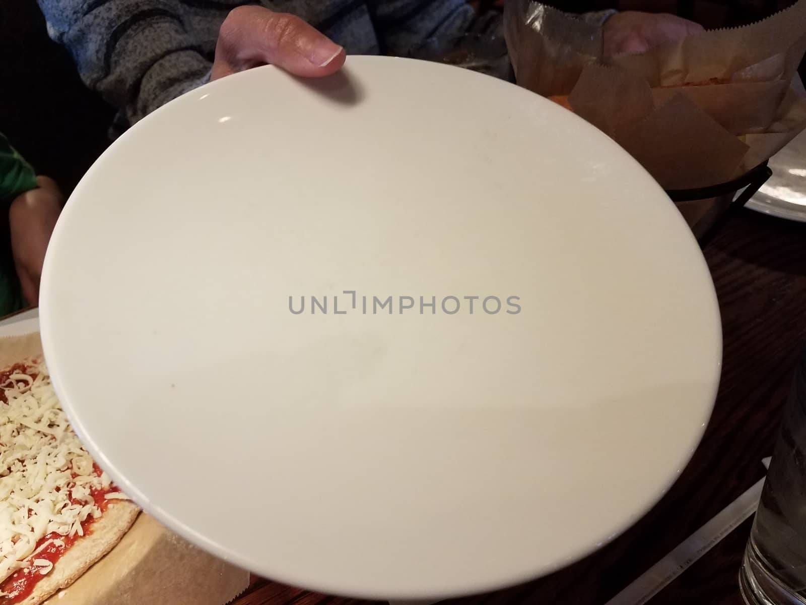 female hand holding large white plate and pizza with cheese