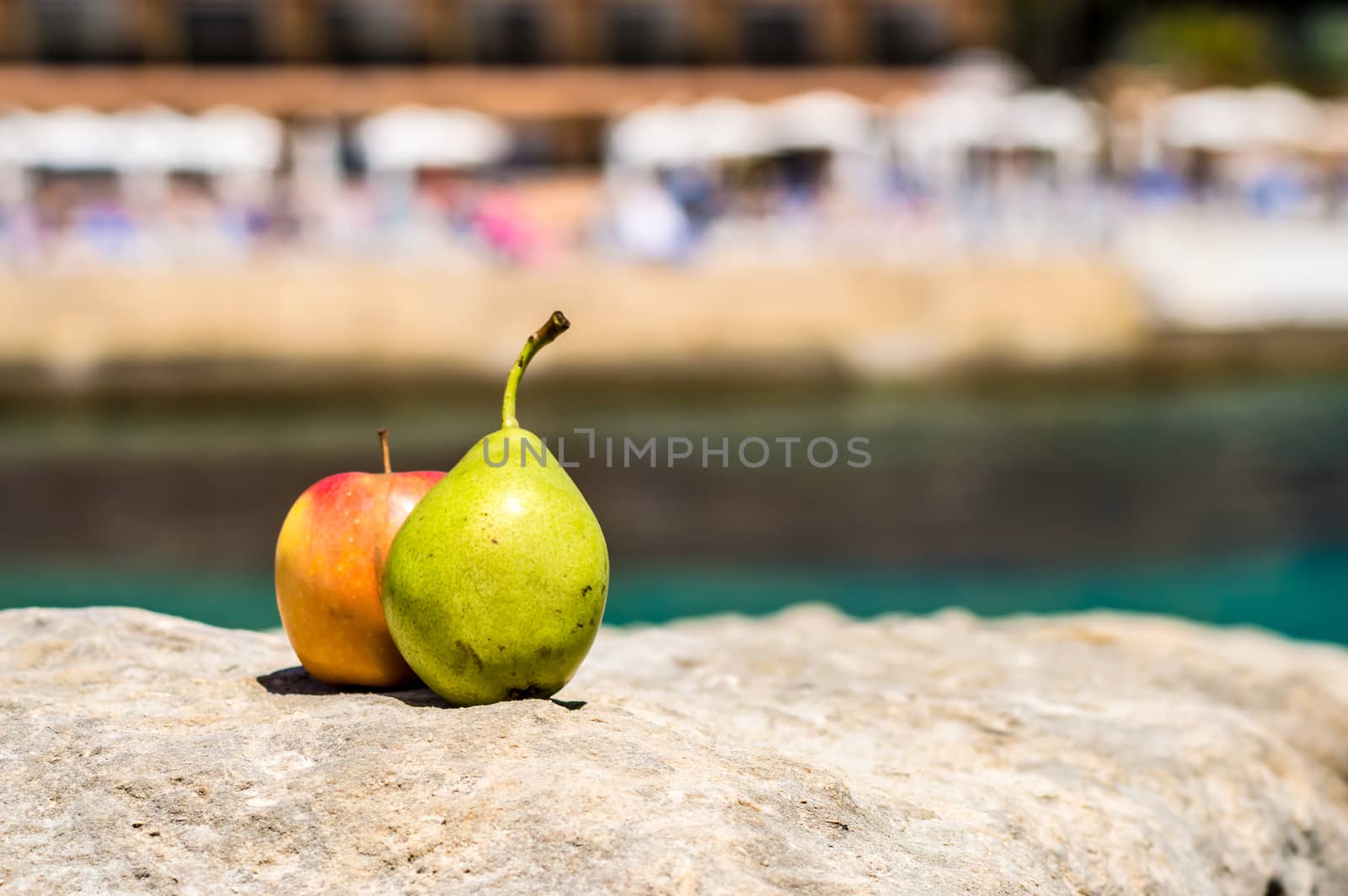 A pear and an apple on a rock facing the sea and a terrace