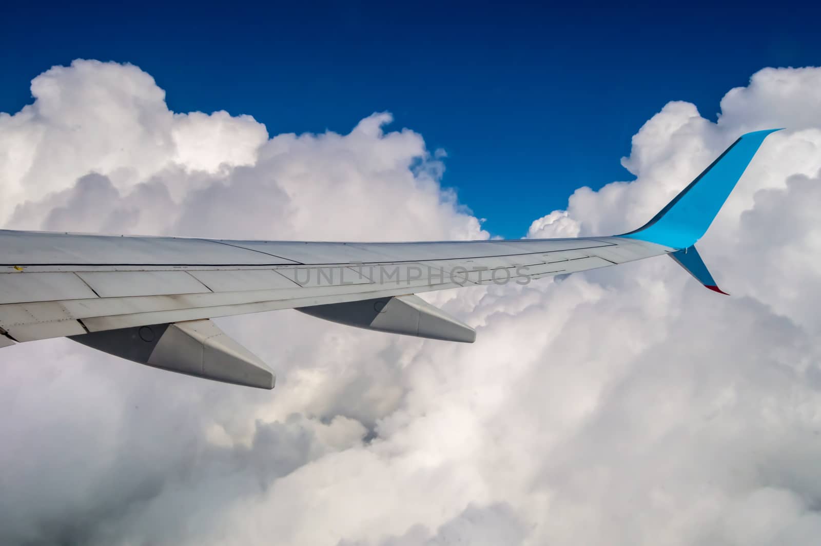 Wing of an airplane in a sky mix of blue sky and clouds