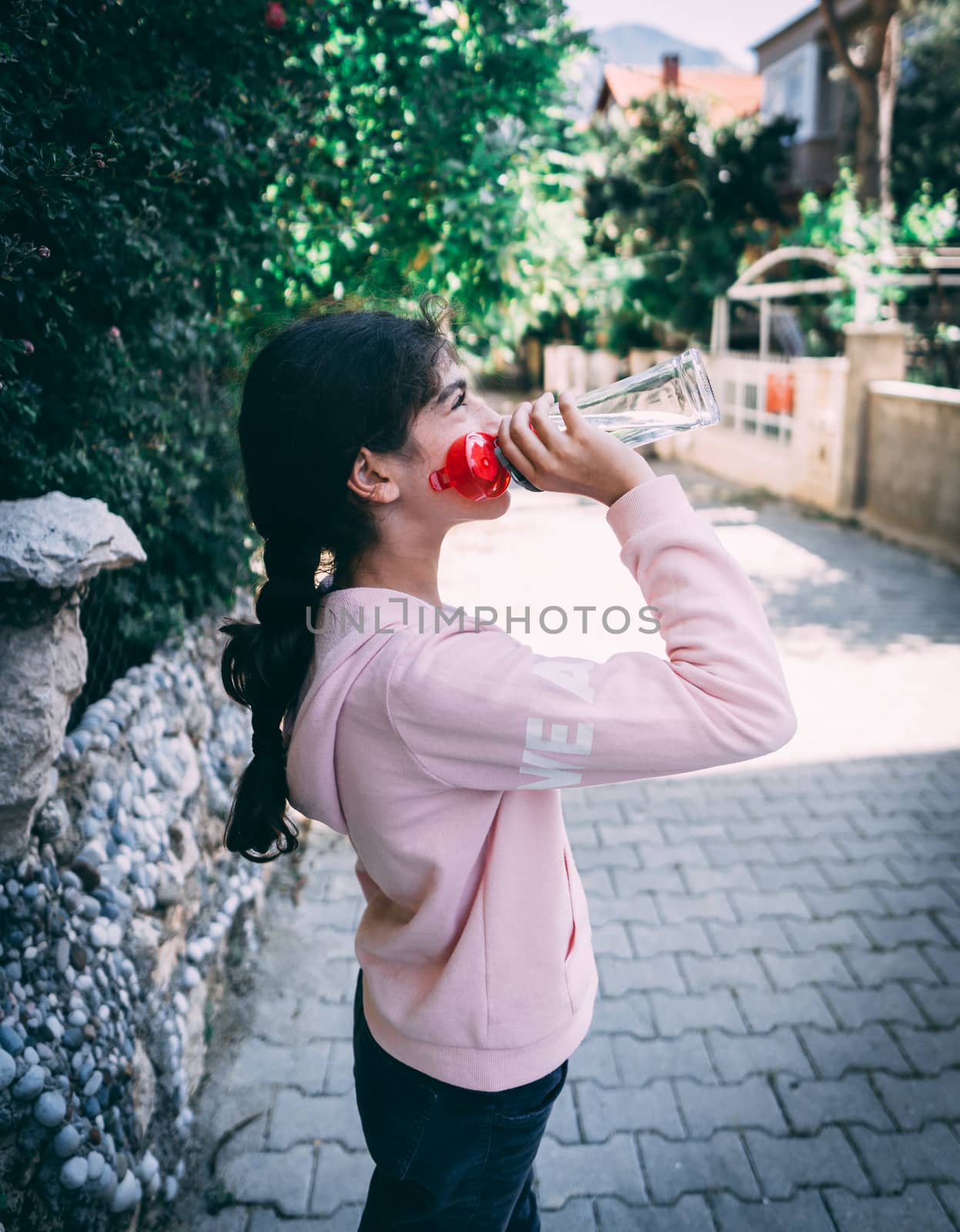 Caucasian young girl holding bottle with water.