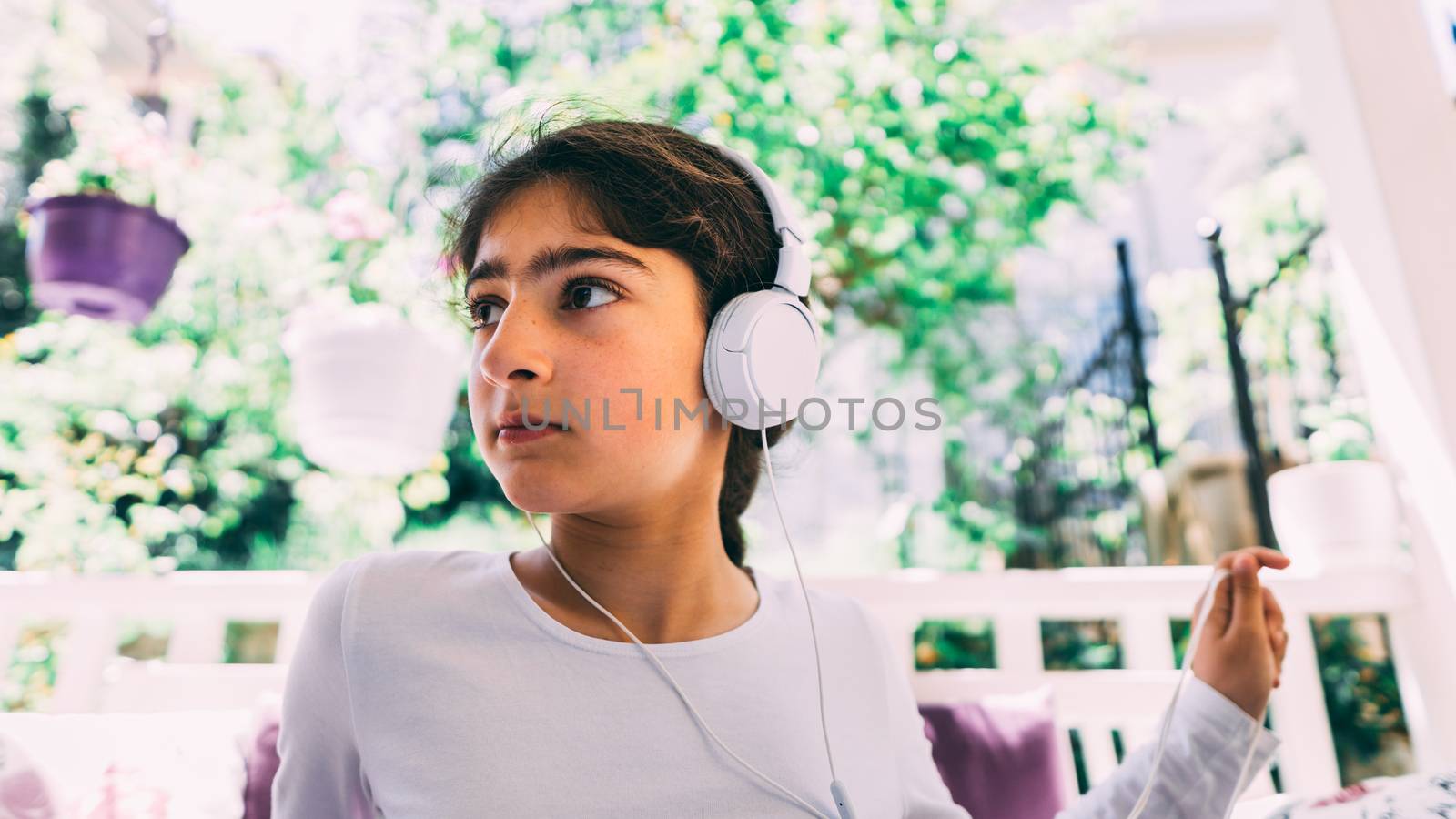 She seats outside in the garden, wearing headphones.