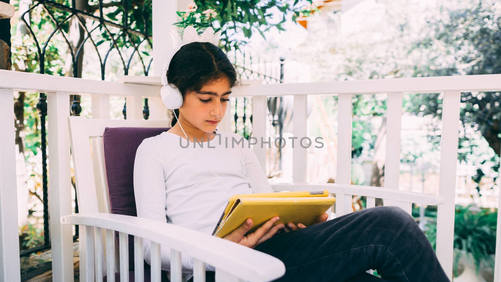 She seats outside in the garden, wearing headphones.