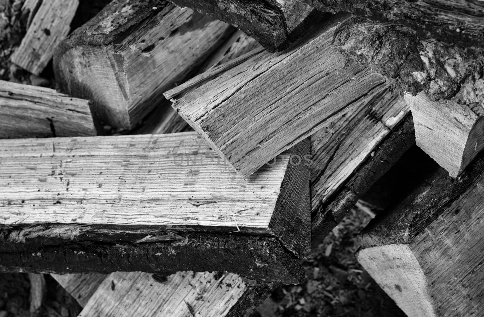 Monochrome view of a jumbled stack of cut and split oak firewood.