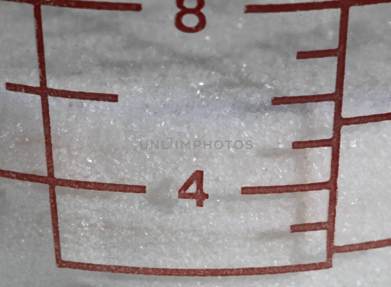 Closeup of measuring marks for white cane sugar in cup.
