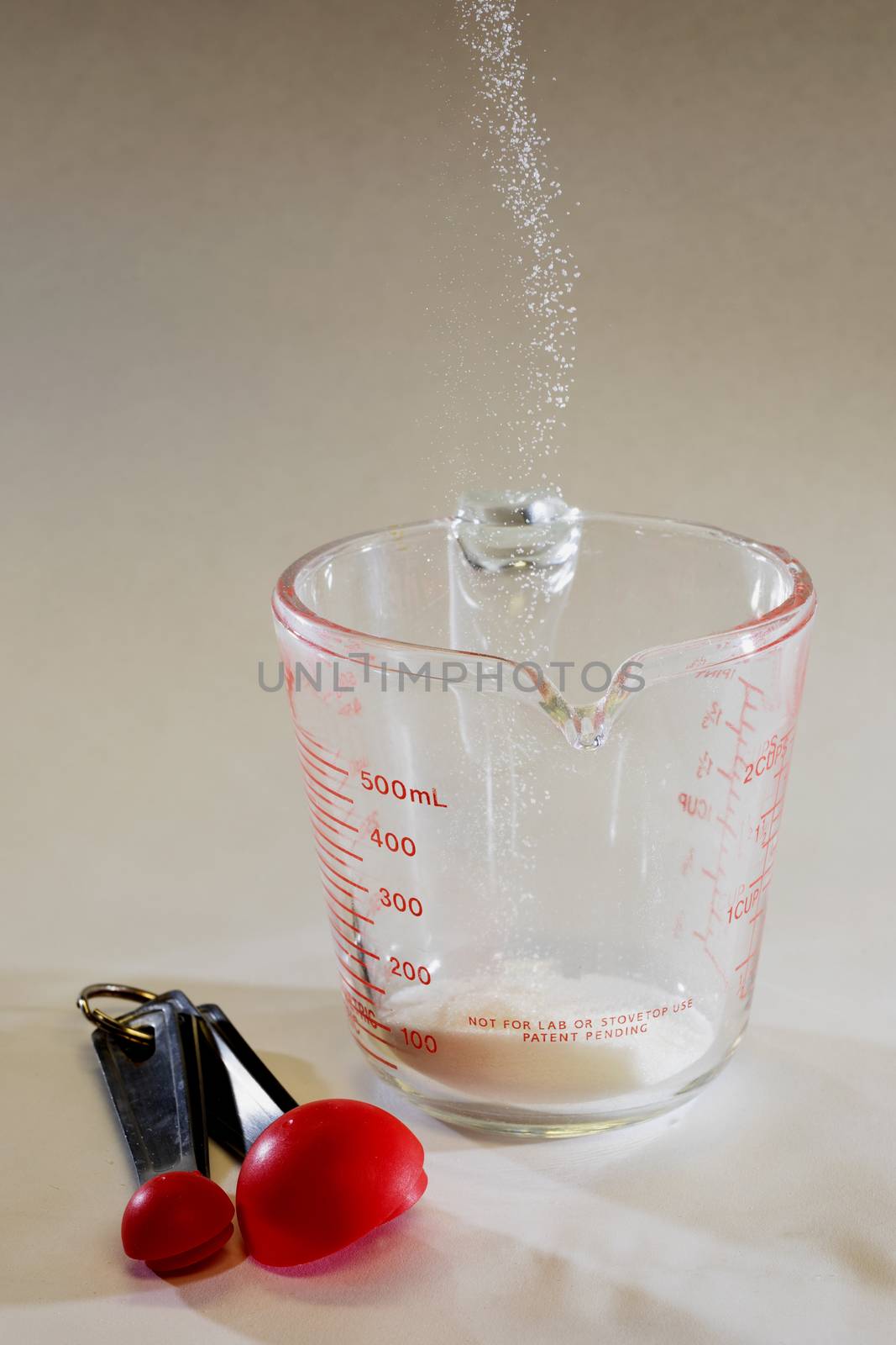Stop motion shot of cane sugar being poured into measuring cup.