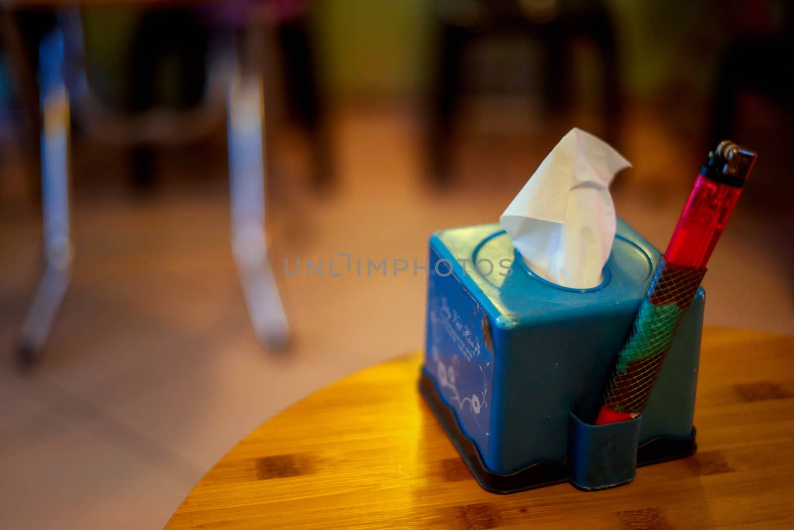blue plastic tissue box with double lighter held on the side on a table inside a bar