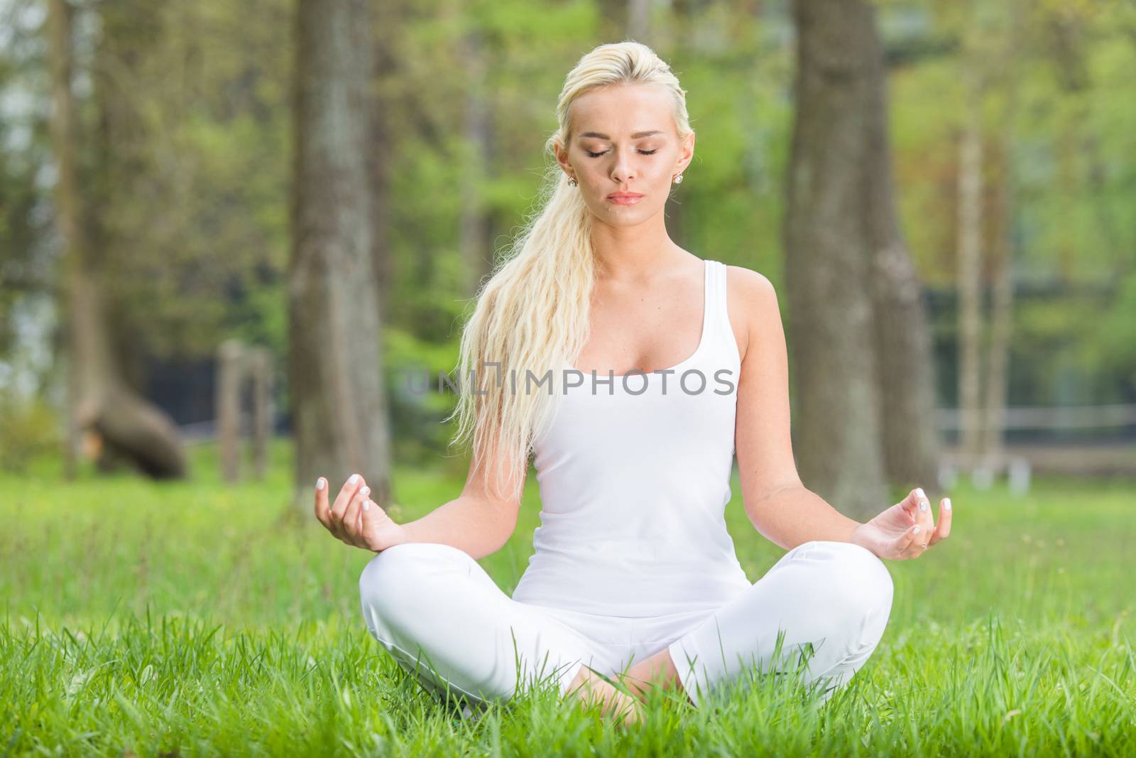 Young woman doing lotus yoga in spring park