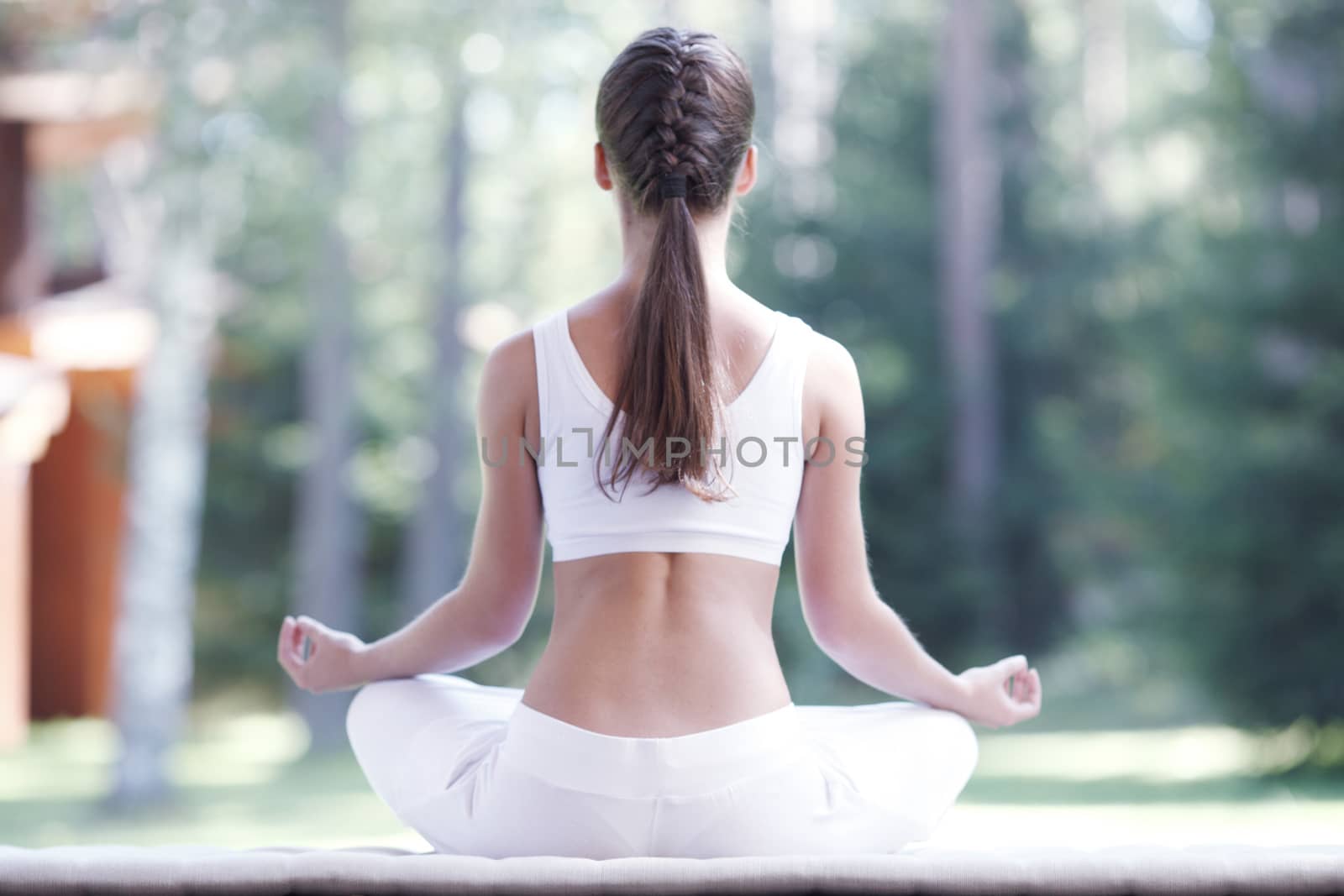 Young woman practicing yoga lotus exercise outdoors