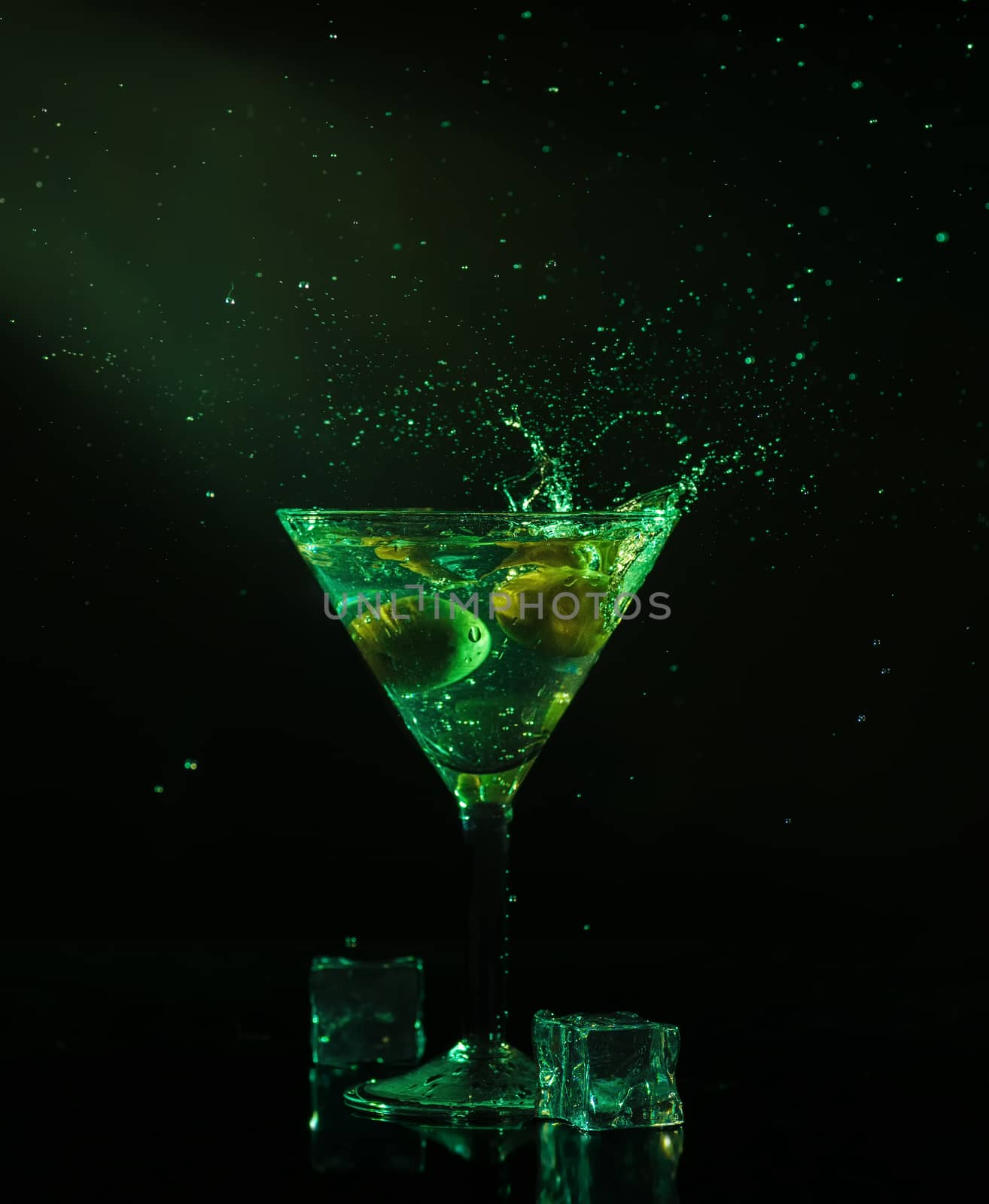 A glass of martini with ice cubes on a club background