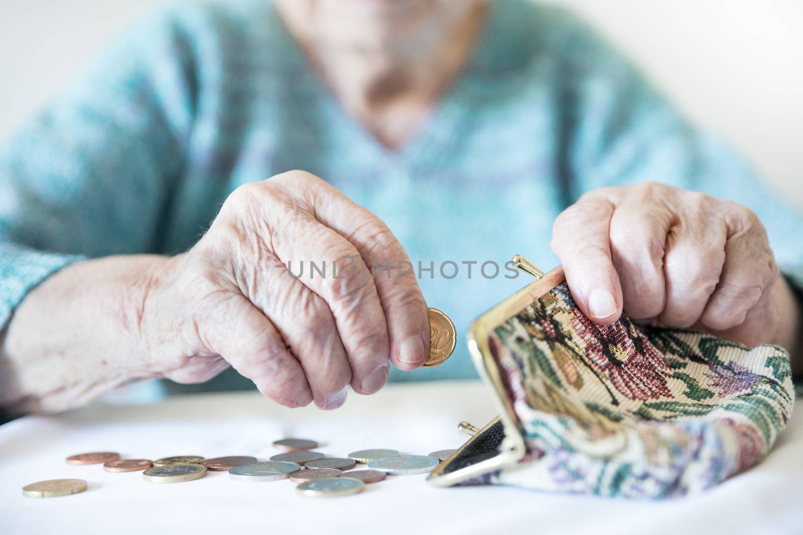 Detailed closeup photo of elderly 96 years old womans hands counting remaining coins from pension in her wallet after paying bills. Unsustainability of social transfers and pension system.