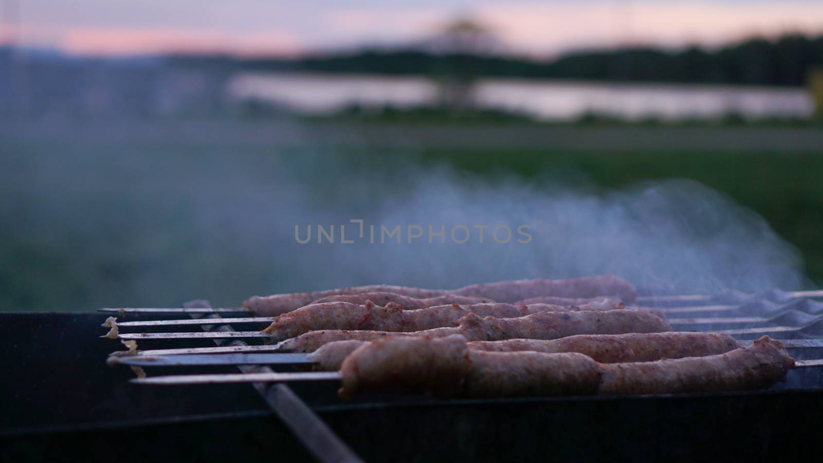 Grilling sausages at sunset outdoors gathering with friends and family. Sunner time