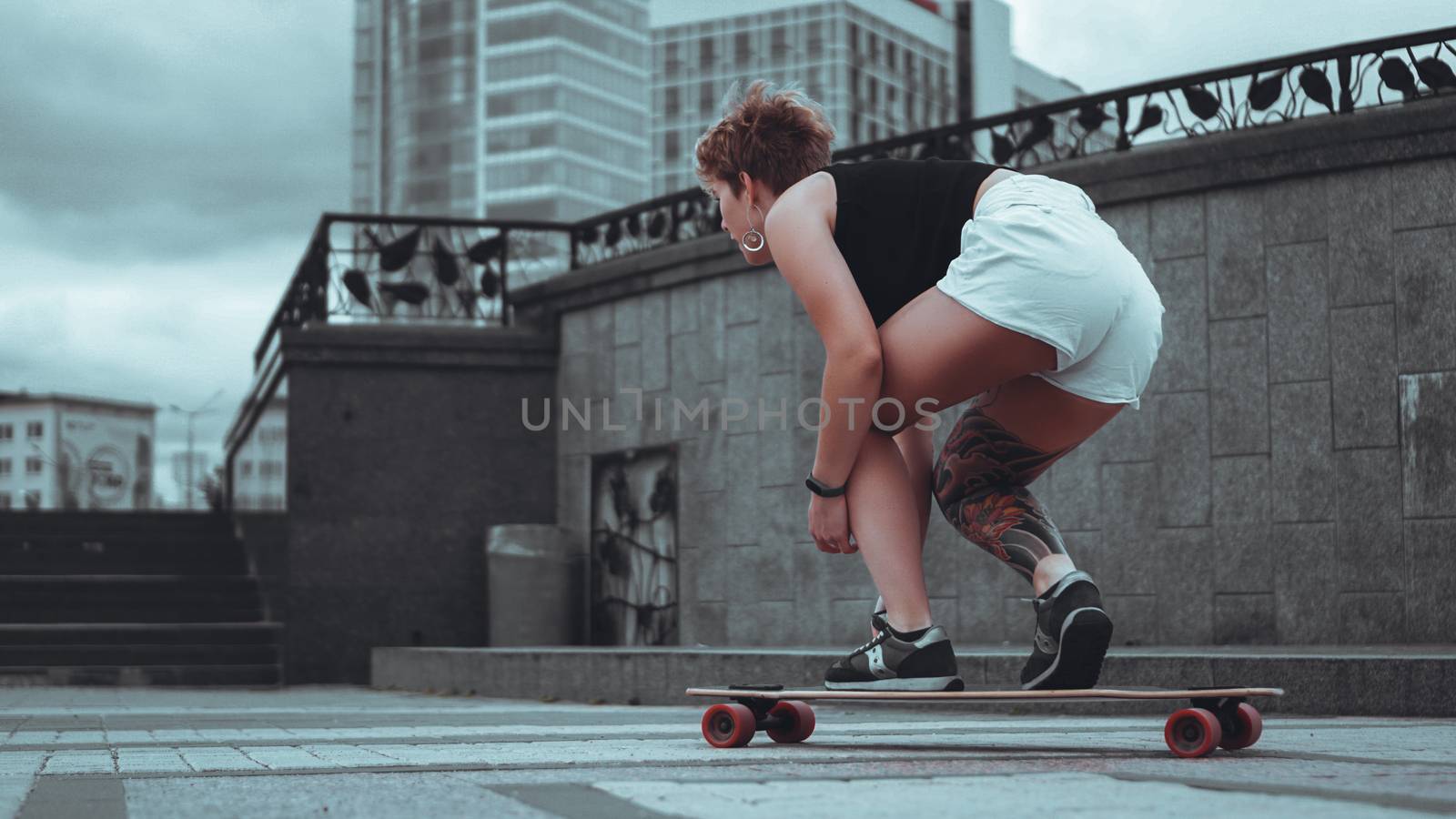 Beautiful young girl with tattoos sits on longboard by natali_brill