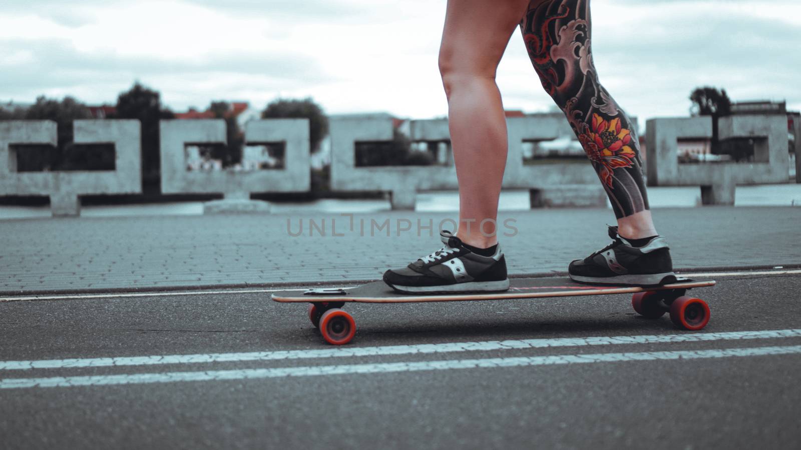 Beautiful young girl with tattoos with longboard in the town. She has traditional japanese tattoo