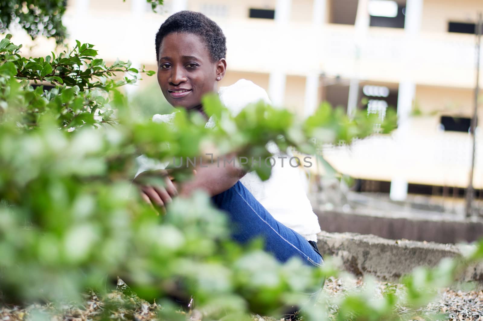 young smiling woman sitting behind the foliage.