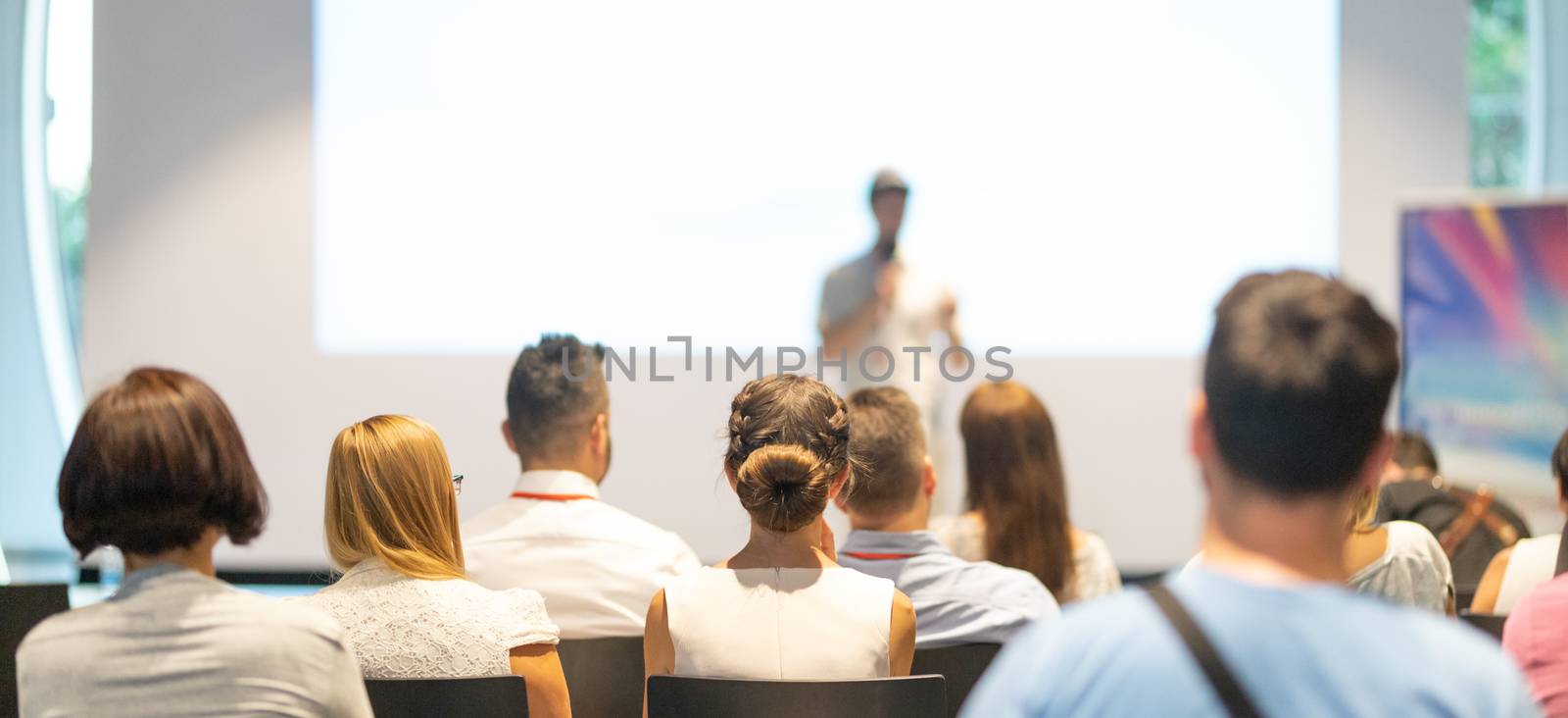 Male speaker giving a talk in conference hall at business event. Audience at the conference hall. Business and Entrepreneurship concept. Focus on unrecognizable people in audience.